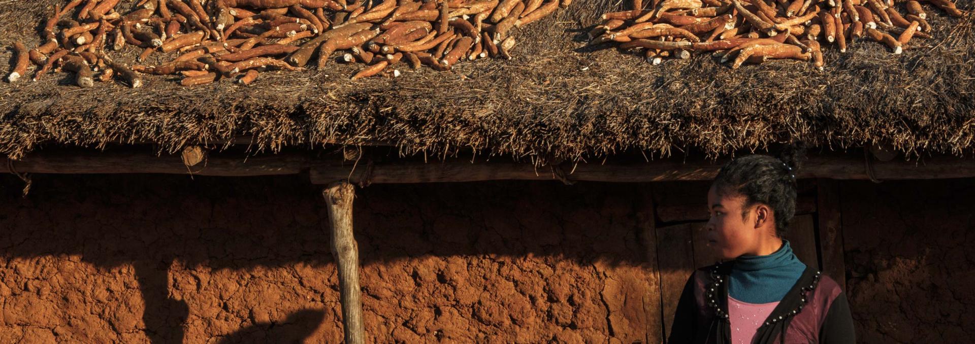 una mujer frente a una choza en la que han guardado la cosecha de mandioca en Madagascar