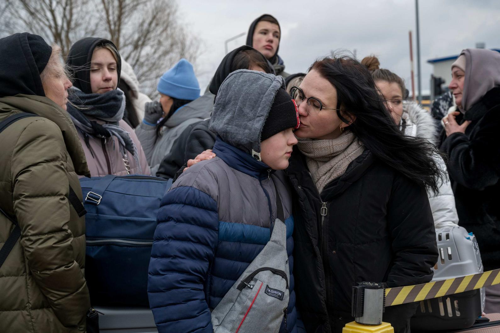 una madre refugiada besa a su hijo mientras esperan un autobús que los evacúe de Ucrania