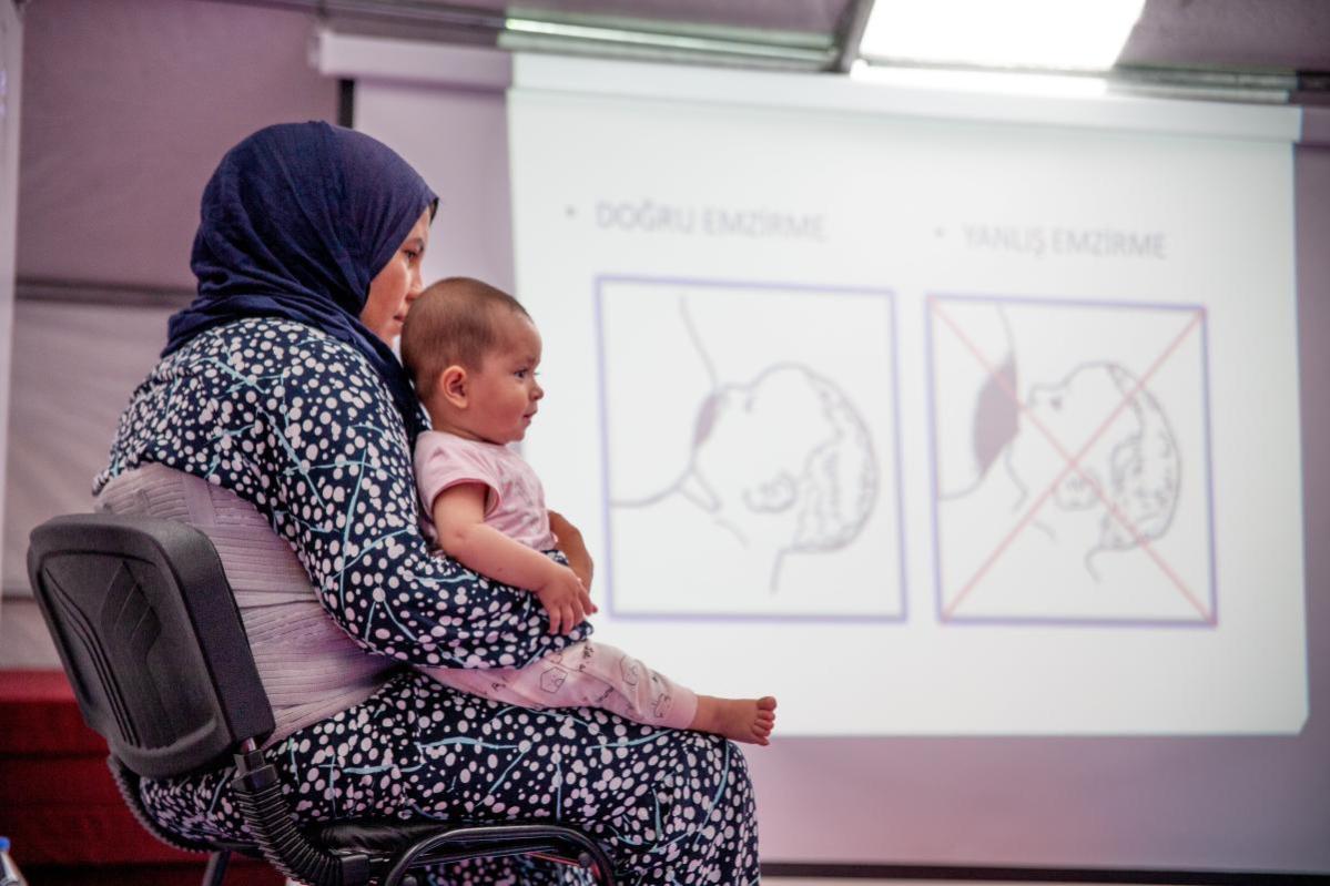   Una madre afectada por los devastadores terremotos en Turquía atiende una formación sobre técnicas para la lactancia materna junto a su bebé en un campo para desplazados © Elisa Bernal para Acción contra el Hambre